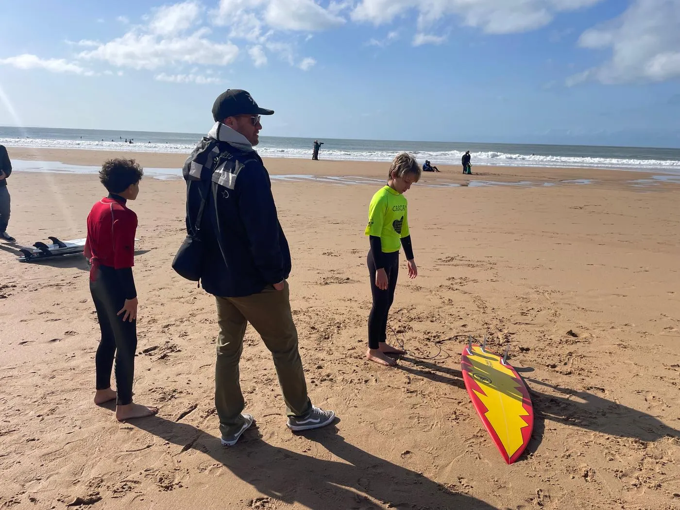 Justin walking to the water with two young surfers