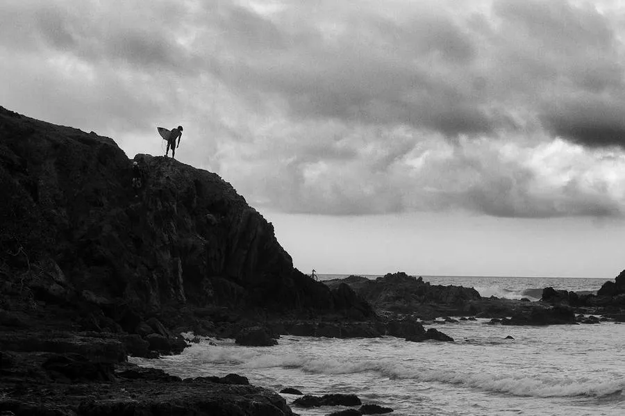 Silhouette on the cliff with a board